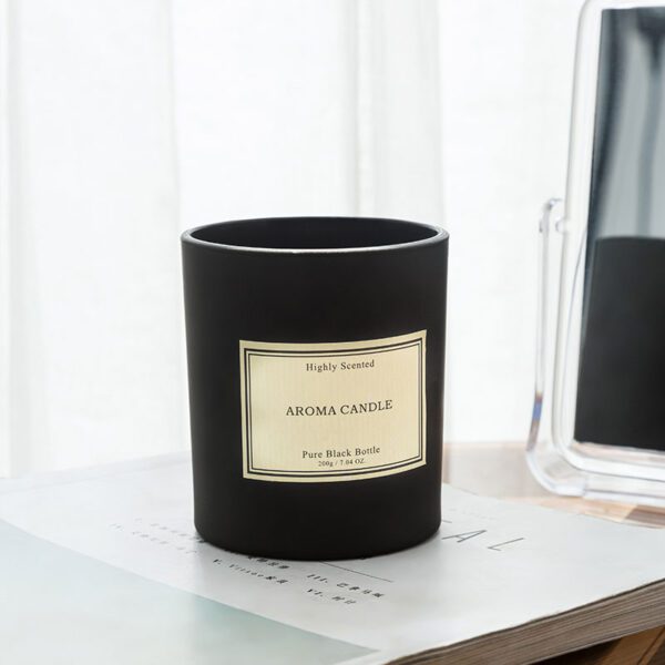Black glass scented candle on a book with soft daylight