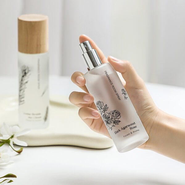 Hand holding botanical room spray bottle in Dark Agarwood Rose scent