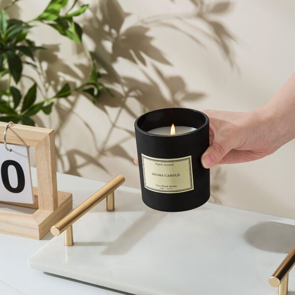 Hand lighting black jar candle in a cozy interior