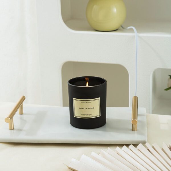Black scented candle burning gently on white tray decor