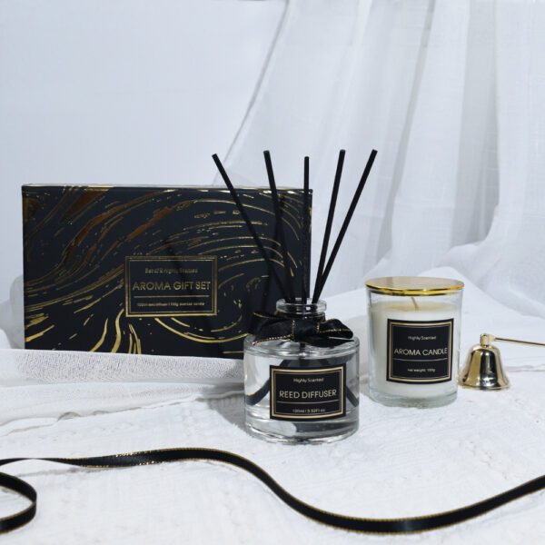 Black and gold aroma gift set with reed diffuser and candle on black fabric
