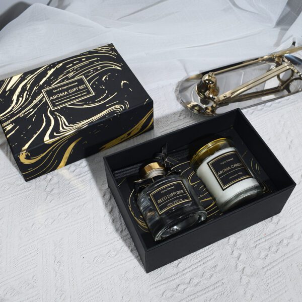 Open black gift box showing diffuser and candle with gold trimming