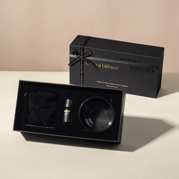 black gift box with gold ribbon and fragrance bottle