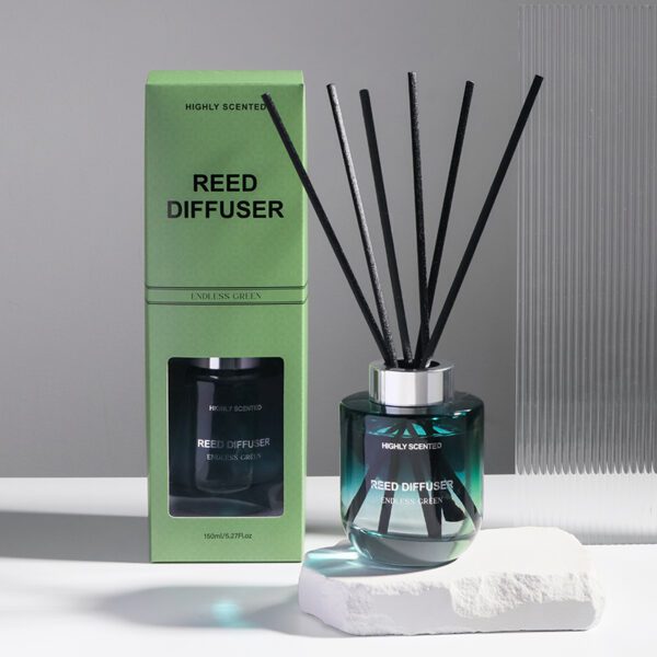 Green glass reed diffuser labeled "Endless Green", paired with sleek light green box, standing on white stone